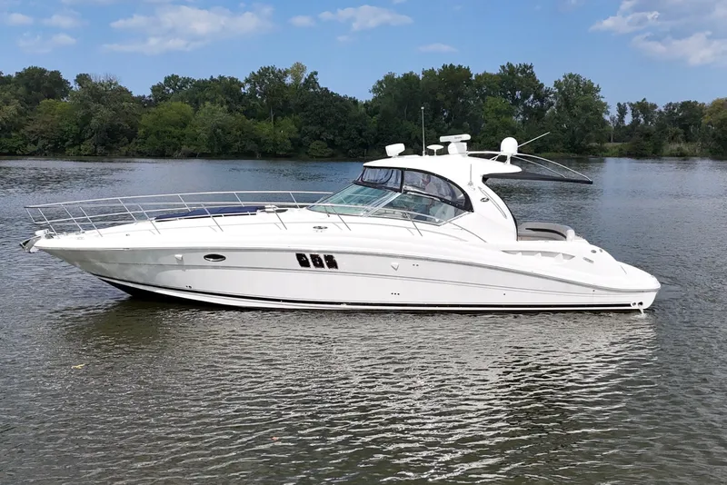 The Image of 2007 Sea Ray 44 Sundancer yacht on a serene lake with lush green trees. - 0