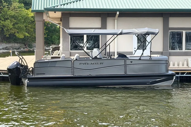 The Image of 2027 Premier 230 Sunsation RL - CL pontoon boat docked by a lakeside building. - 1