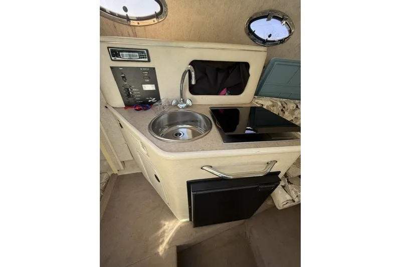 Slide: The Image of Compact kitchenette inside a 2000 Sea Ray 240 Sundancer boat, featuring sink and stove. - 19