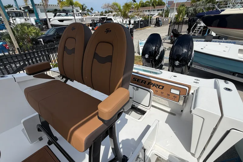 Slide: The Image of 2027 Sea Pro 262 DLX boat with dual engines and brown seating, displayed outdoors. - 9
