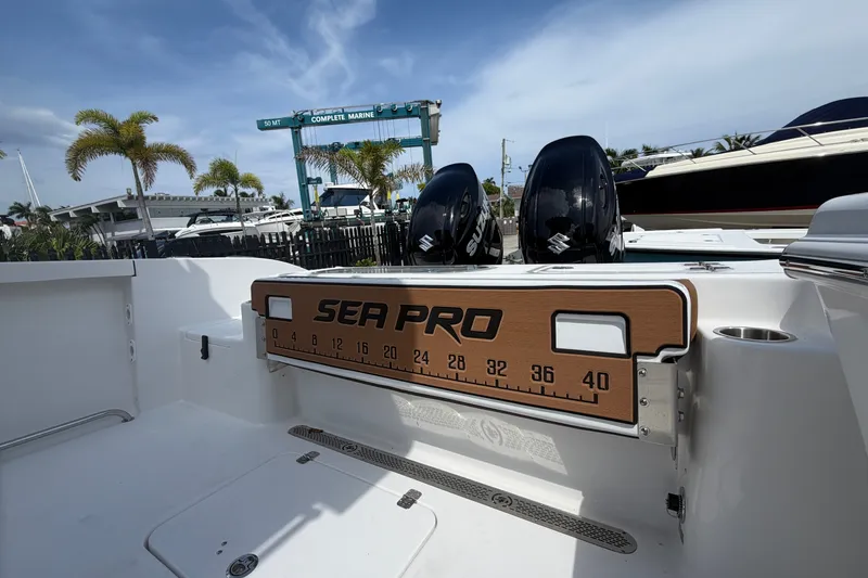 Slide: The Image of 2027 Sea Pro 262 DLX boat with dual Suzuki engines, docked near palm trees. - 13