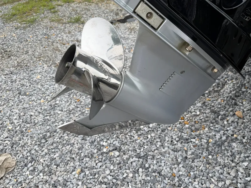 Slide: The Image of A silver boat motor propeller on a gravel surface, part of an outboard motor. - 21
