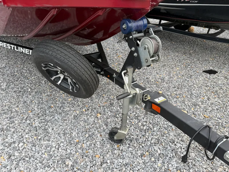 Slide: The Image of A Crestliner CXF 189 boat trailer with a winch and spare tire on gravel. - 24