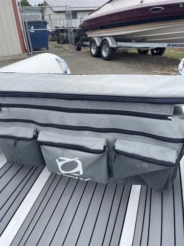 Slide: The Image of A gray bag with multiple zippered pockets sits on a boat's floor. - 16