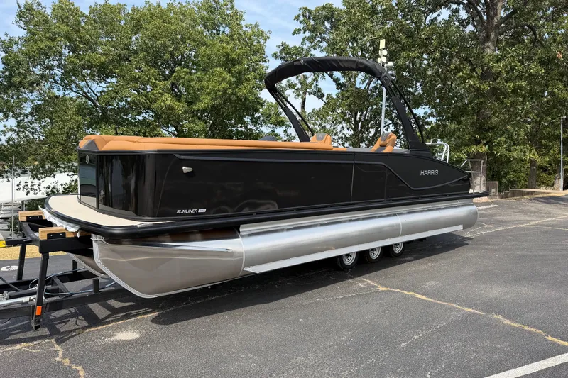Slide: The Image of 2027 Harris Sunliner 250 pontoon boat on trailer, parked outdoors with trees in background. - 2