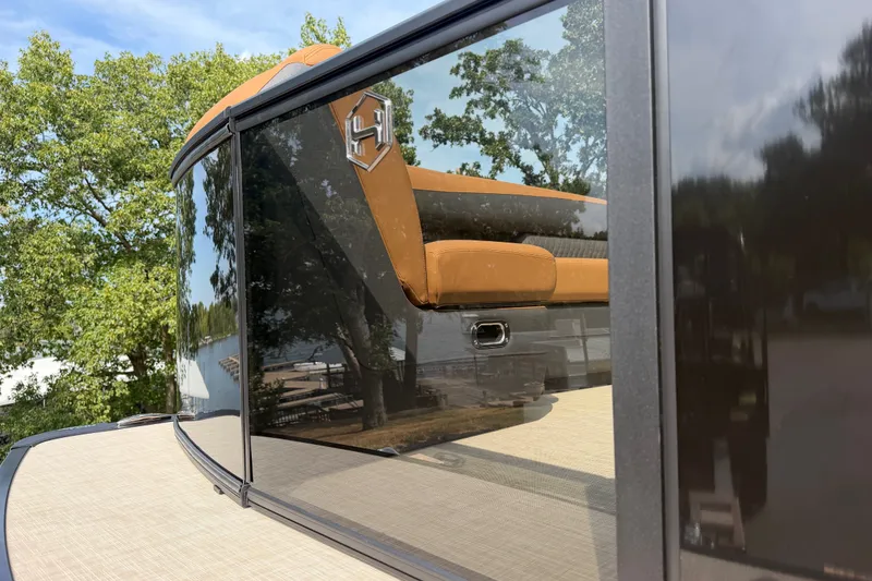 Slide: The Image of 2027 Harris Sunliner 250 boat with sleek design and reflective surfaces, surrounded by trees. - 4
