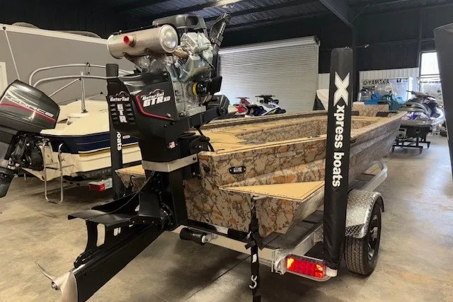 Slide: The Image of 2026 Xpress Bayou 180 boat with camouflage design in a showroom. - 4