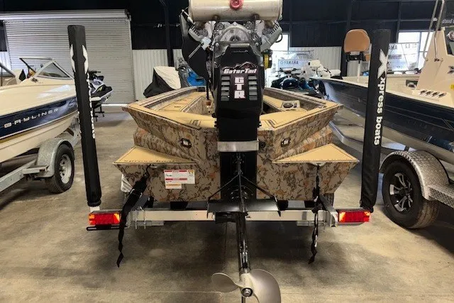 Slide: The Image of 2026 Xpress Bayou 180 boat with camo design and Gator Tail motor in showroom. - 9