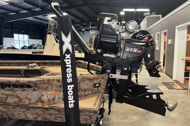Slide: The Image of 2026 Xpress Bayou 180 boat with camo design and powerful outboard motor in showroom. - 5