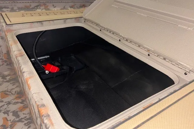 Slide: The Image of Open storage compartment in 2026 Xpress Bayou 180 boat, featuring a camo design. - 14