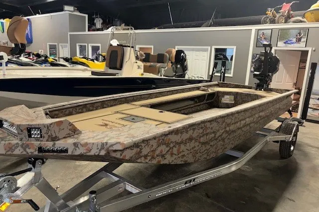 Slide: The Image of 2026 Xpress Bayou 180 boat with camouflage design on a trailer in a showroom. - 3