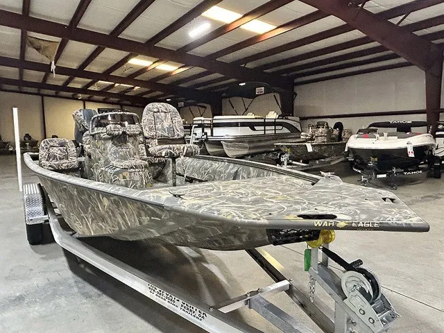 Slide: The Image of A War Eagle 2170 Blackhawk boat in a warehouse, featuring camouflage pattern and on a trailer. - 2