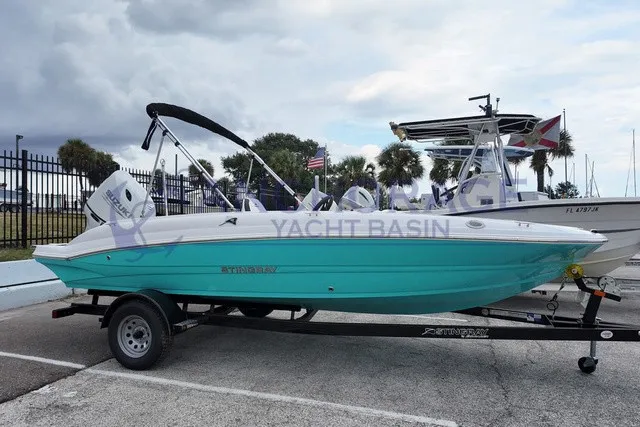 The Image of A turquoise 2027 Stingray 19SC on a trailer at a yacht basin. - 1
