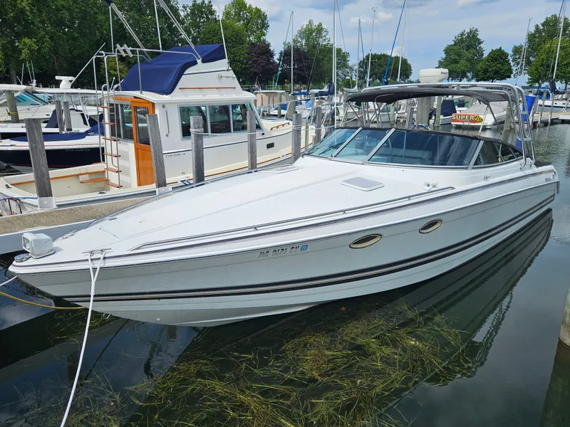 The Image of A white motorboat docked, surrounded by other boats and trees. - 2