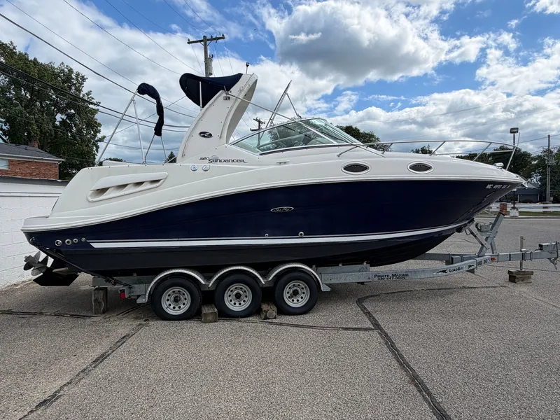 The Image of A 2006 Sea Ray Sundancer 260 on a trailer. It features a blue and white hull design. - 0