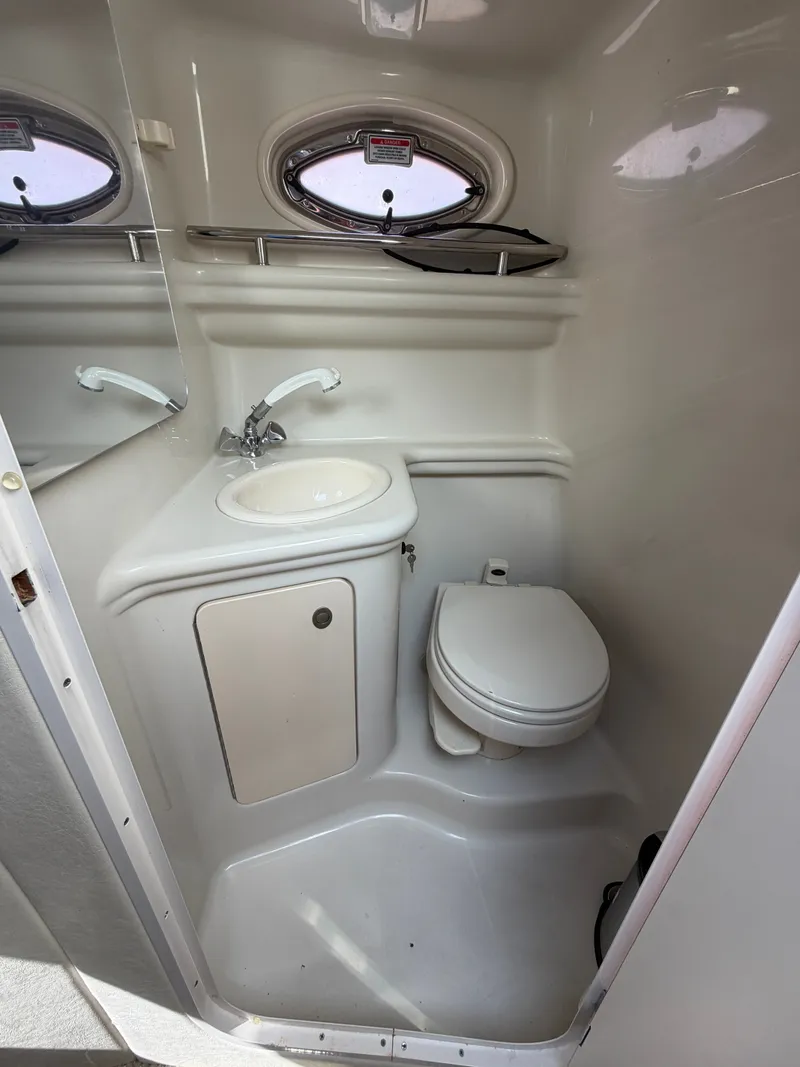 Slide: The Image of The image shows a compact boat bathroom with a sink, toilet, and porthole window. - 14