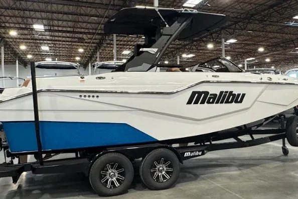 Slide: The Image of 2026 Malibu M230 boat on trailer in warehouse, showcasing sleek design and modern features. - 2