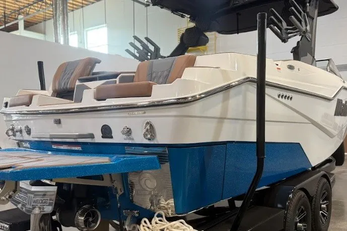 Slide: The Image of 2026 Malibu M230 boat with sleek design, blue hull, and modern seating in a showroom. - 4