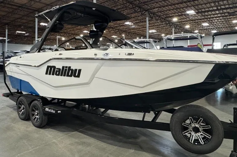 The Image of 2026 Malibu M230 boat on trailer in showroom, featuring sleek design and modern features. - 1