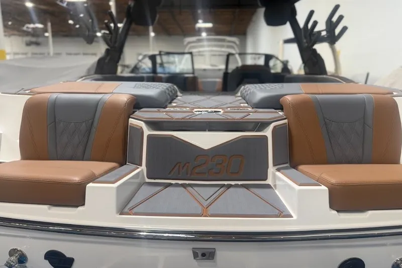 Slide: The Image of 2026 Malibu M230 boat interior with luxurious brown and gray seating. - 11