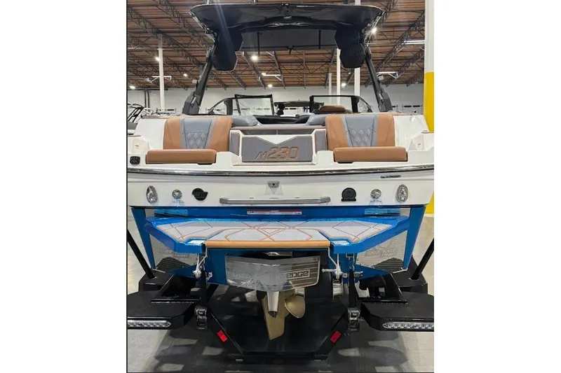 Slide: The Image of 2026 Malibu M230 boat rear view in a showroom, showcasing seating and design features. - 9