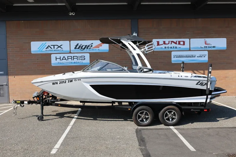 The Image of 2020 Tigé R20 boat on trailer, parked in front of dealership signs. - 1