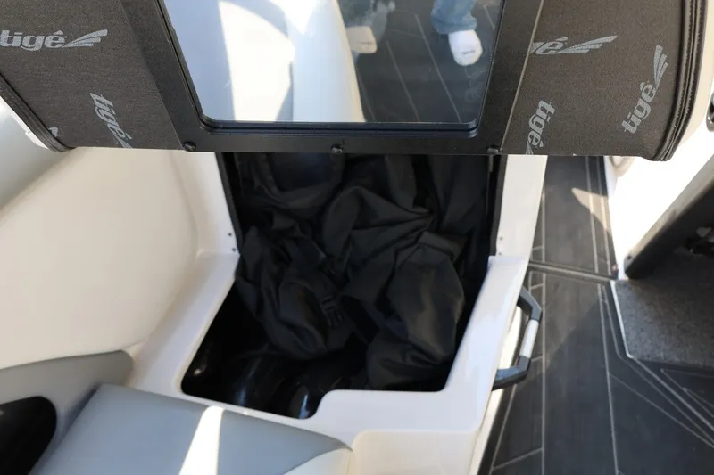Slide: The Image of Storage compartment in a 2020 Tigé R20 boat, featuring black interior and branded cover. - 28