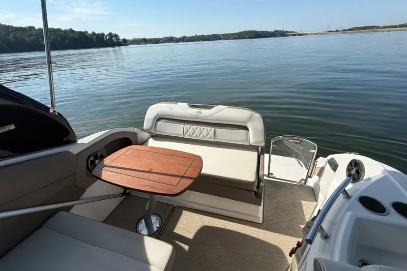 Slide: The Image of 2018 Regal 28 Express boat interior with seating and table on a calm lake. - 15