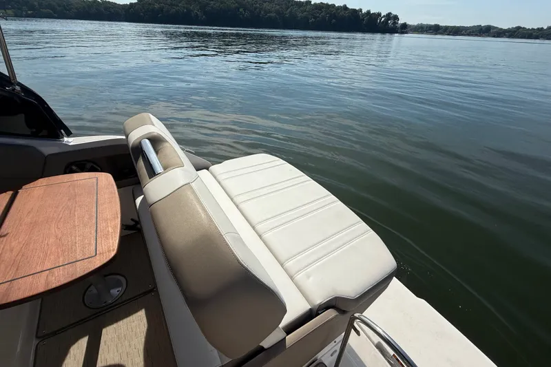 Slide: The Image of 2018 Regal 28 Express boat interior with seating and wooden table on a calm lake. - 14