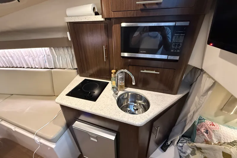 Slide: The Image of Compact kitchen area in a 2018 Regal 28 Express boat with sink, stove, and microwave. - 23