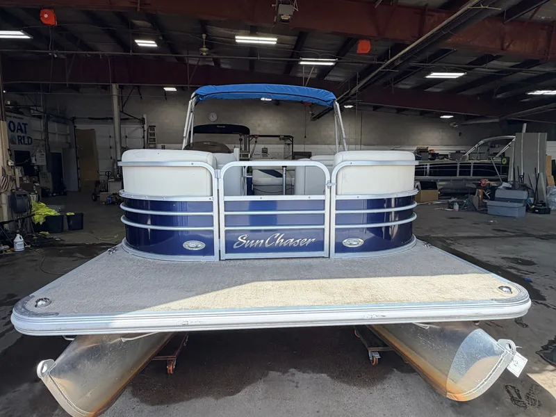 Slide: The Image of A 2015 SunChaser pontoon boat in a warehouse. It features blue and white detailing. - 36