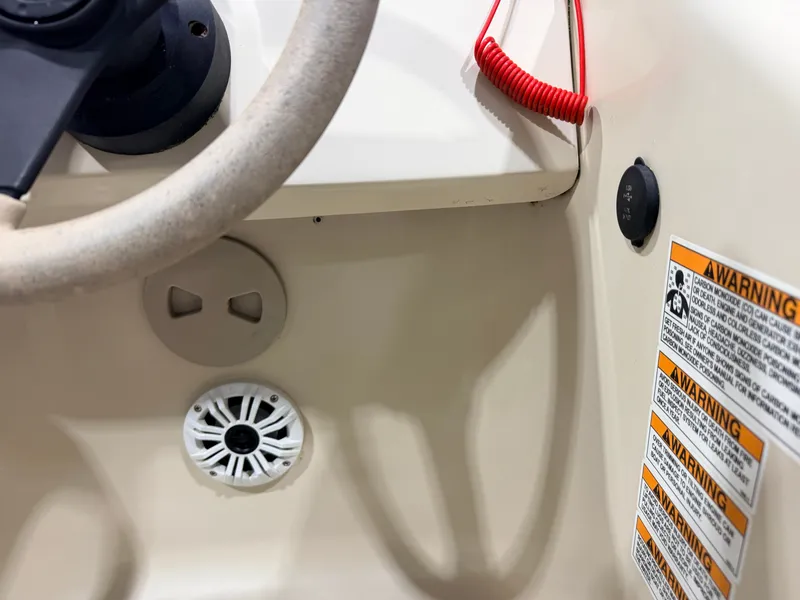 Slide: The Image of Close-up of the helm area with steering wheel, speaker, and warning labels. - 23