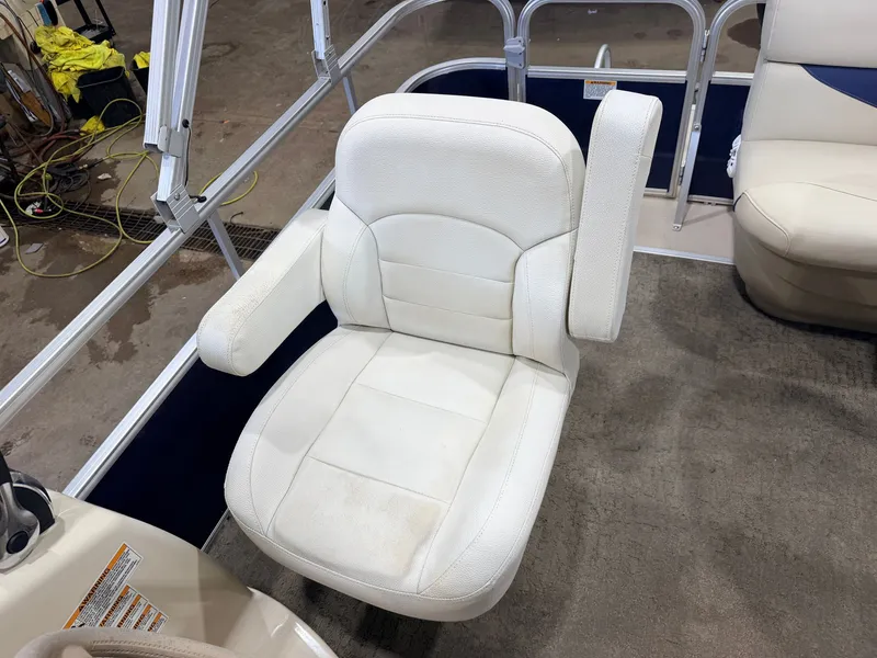 Slide: The Image of A white captain's chair on a boat with armrests and carpeted flooring. - 18