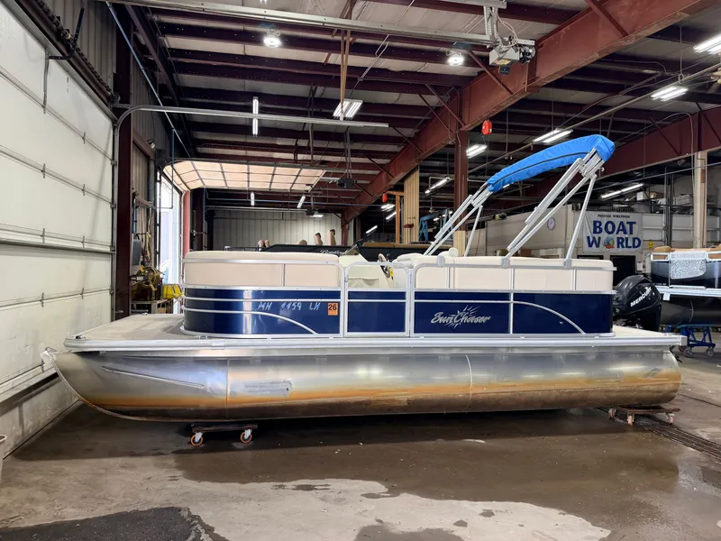 Slide: The Image of A 2015 SunChaser 8520 Classic Cruise pontoon boat in a warehouse, featuring a blue canopy. - 39