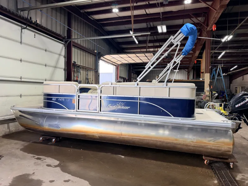 Slide: The Image of A 2015 SunChaser pontoon boat in a warehouse. It features blue and white accents. - 41