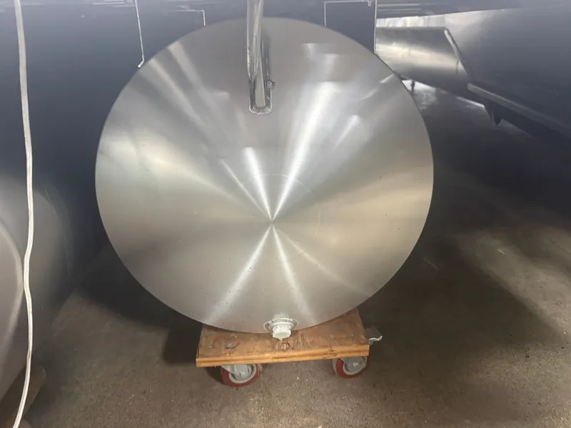 Slide: The Image of A silver, round metal cylinder on a wheeled cart in a warehouse setting. - 32