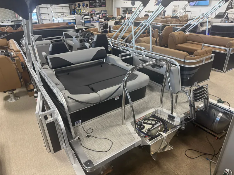 Slide: The Image of A modern pontoon boat with gray and black seating, stainless steel railings, and an engine in a showroom. - 36