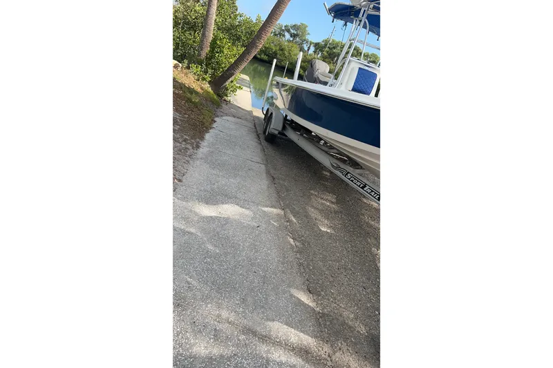 Slide: The Image of 2014 Blue Wave 2300 PureBay boat on trailer near water, surrounded by trees. - 9