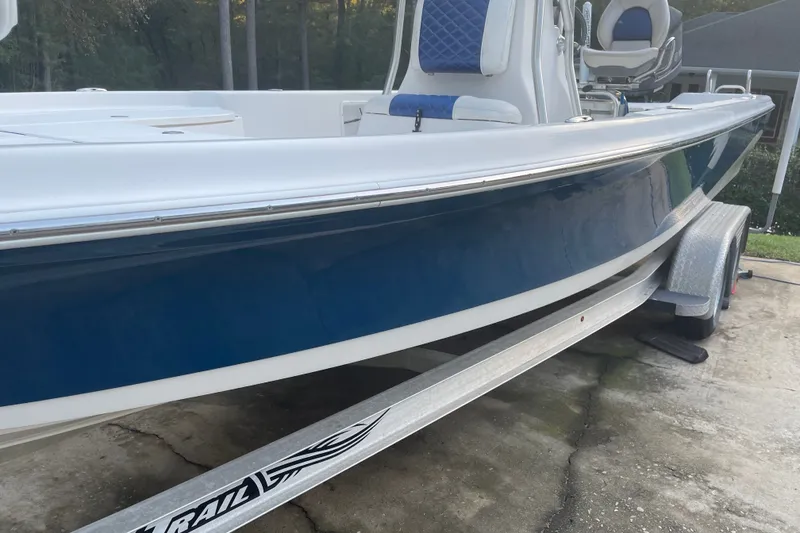 Slide: The Image of 2014 Blue Wave 2300 PureBay boat on trailer, featuring sleek blue and white design. - 5