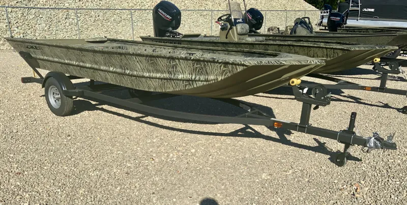 The Image of A 2027 Tracker Grizzly 1754 boat on a trailer, featuring a camo design and outboard motor. - 1