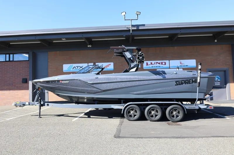 Slide: The Image of 2022 Supreme ZS252 boat on trailer, parked outside a building. - 2