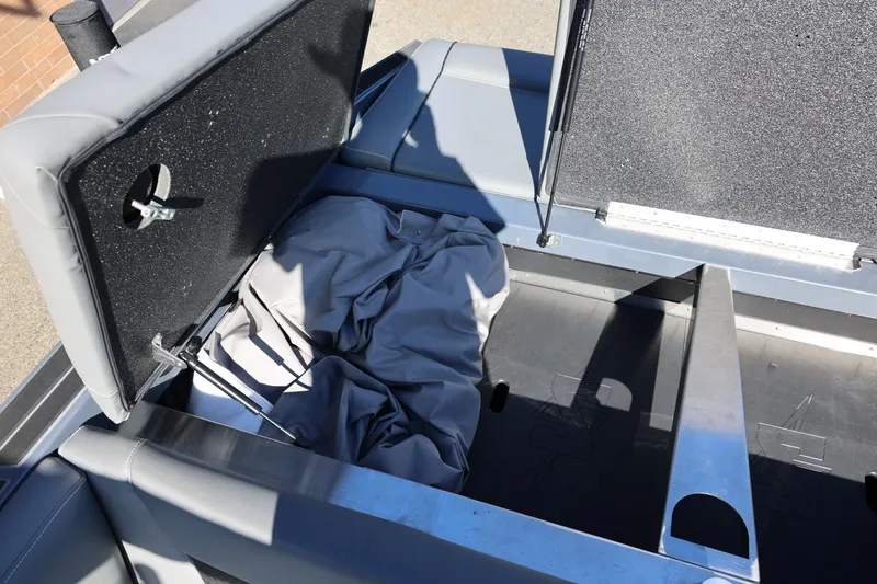 Slide: The Image of Open storage compartment in 2022 Supreme ZS252 boat, featuring gray interior and fabric cover. - 22