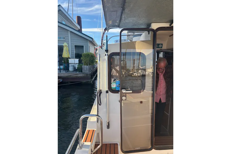 Slide: The Image of 2007 Ranger Tug R-25 docked, with a person exiting through the cabin door. - 12