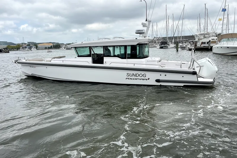 Slide: The Image of 2023 Axopar 37 XC Cross Cabin boat on water, docked in a marina. - 3