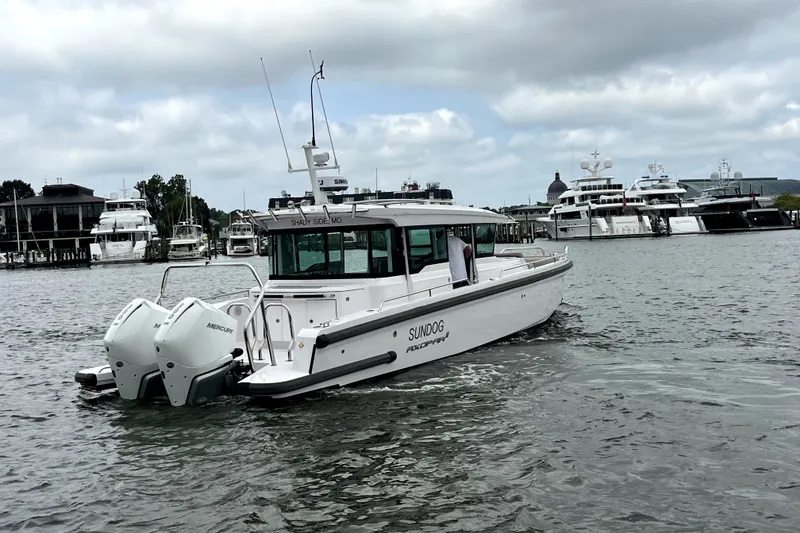 Slide: The Image of 2023 Axopar 37 XC Cross Cabin boat cruising in a marina with yachts in the background. - 5