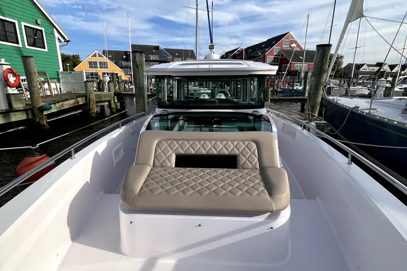 Slide: The Image of 2023 Axopar 37 XC Cross Cabin boat docked, featuring a cushioned seating area. - 28