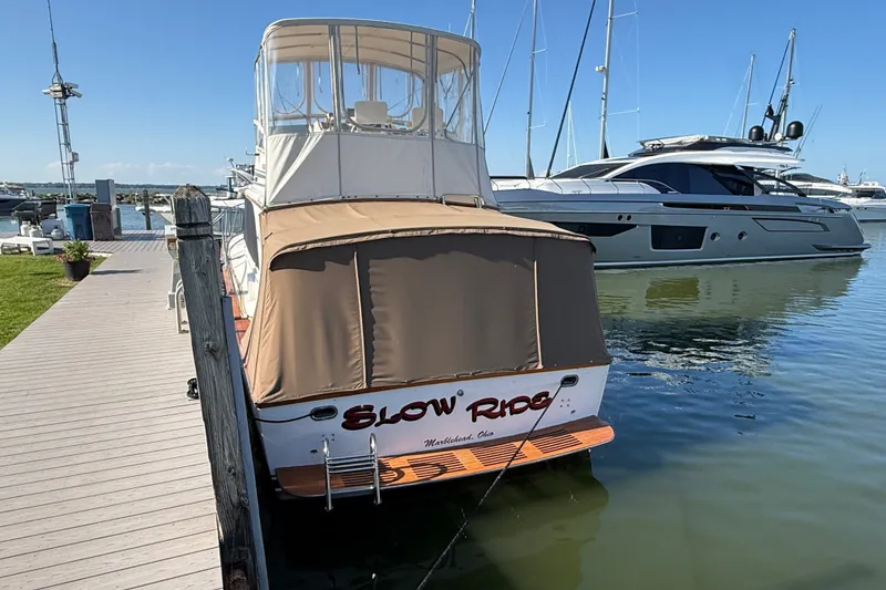 Slide: The Image of 1984 Egg Harbor 40 Sedan docked at marina, featuring covered deck and calm waters. - 5