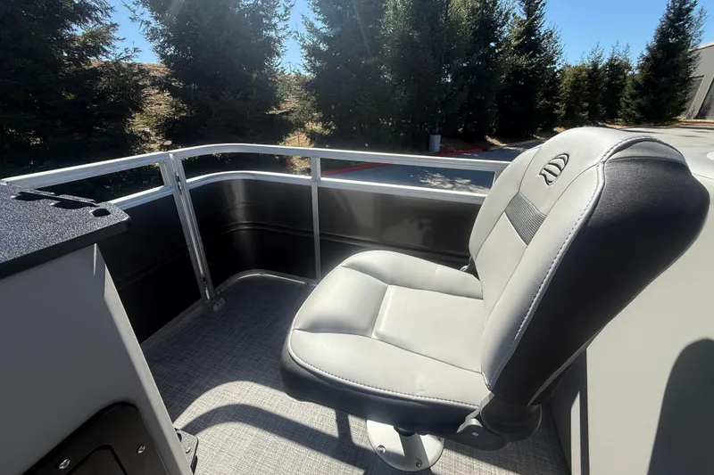 Slide: The Image of 2027 Sun Tracker SportFish 20 DLX boat seat with railing, surrounded by trees. - 30