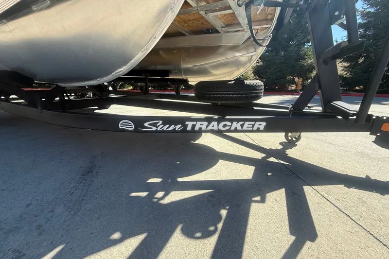 Slide: The Image of 2027 Sun Tracker SportFish 20 DLX trailer on concrete, showcasing brand logo. - 52