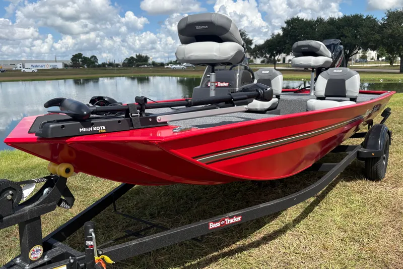 The Image of A red 2027 Bass Tracker Classic XL boat on a trailer beside a pond. - 0